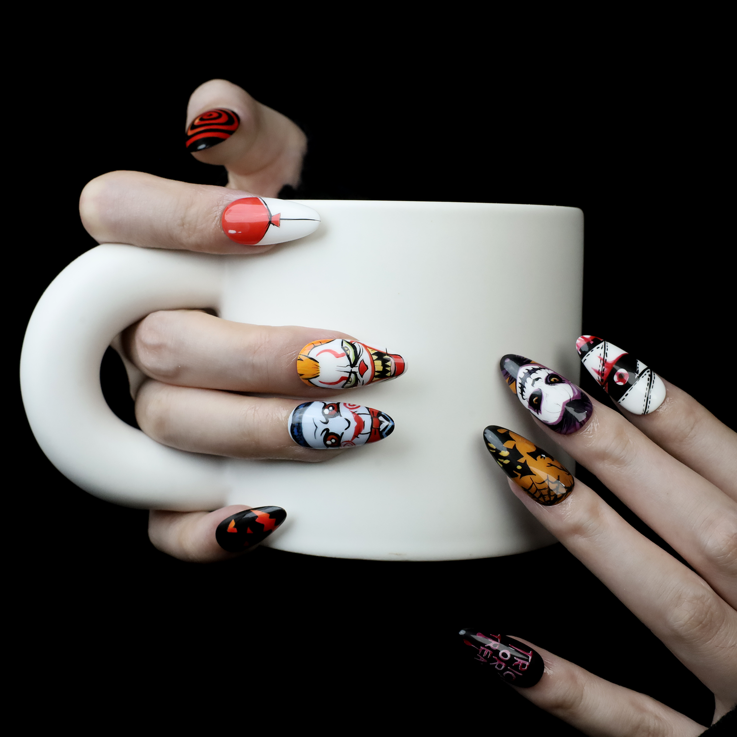 A person holds a large white mug, showing off We Do Nails Spooky Nightmares Halloween Press-On Nails featuring hand-painted pumpkins, ghosts, and scary designs against a plain black background.