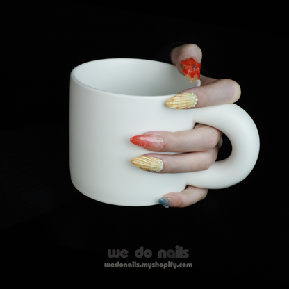 Set against a black backdrop, hands flaunt long, vibrant Exotic Floral Press-On Nails by We Do Nails with 3D floral designs and unique textures. The model wears a black sweater with thumb holes and the text we do nails is partially visible.