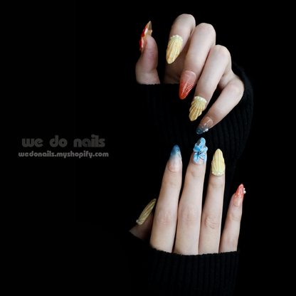 Set against a black backdrop, hands flaunt long, vibrant Exotic Floral Press-On Nails by We Do Nails with 3D floral designs and unique textures. The model wears a black sweater with thumb holes and the text we do nails is partially visible.