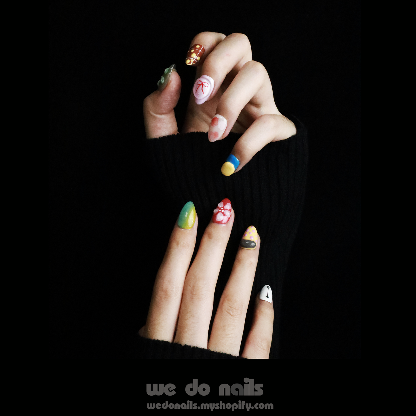 Hands featuring We Do Nails Cute Colorful Press-On Nails, with long, vibrant Baymax Aesthetics-inspired designs and abstract, multi-colored patterns. The individual sports a black sweater against a simple black background for an effortlessly chic look.