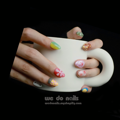 Hands featuring We Do Nails Cute Colorful Press-On Nails, with long, vibrant Baymax Aesthetics-inspired designs and abstract, multi-colored patterns. The individual sports a black sweater against a simple black background for an effortlessly chic look.